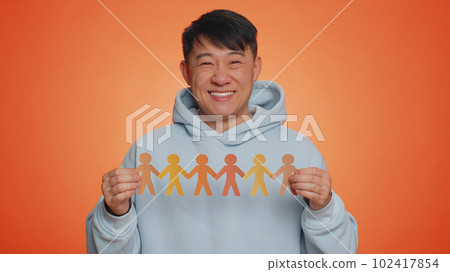 Man showing multiracial different skin color human shape cut out of paper against racism community Man showing multiracial different skin color human shape cut out of paper against racism community 102417854