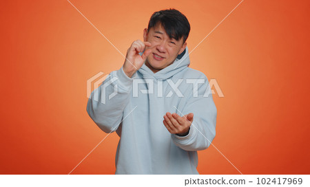 Man showing a little bit gesture with sceptic smile, showing minimum sign, measuring small size 102417969