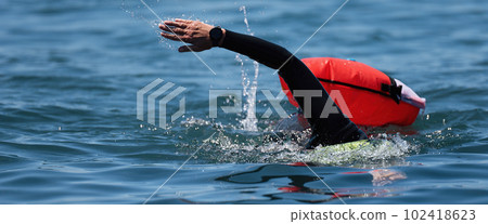 Long distance swimming marathon swimmer in action. Swimming man in clean ocean water. Open water swimming Long distance swimming marathon swimmer in action. Swimming man in clean ocean water. Open water swimming 102418623