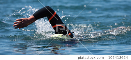 Professional triathlete man swimming in wetsuit crawl in the ocean, freestyle crawl in ocean. Swimming man in clean ocean water. Open water swimming 102418624