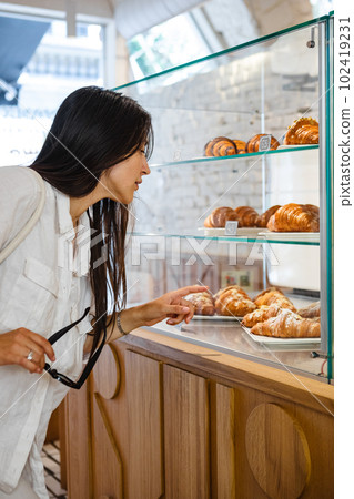 Lady gazes at the bakery counter in cafe Lady gazes at the bakery counter in cafe 102419231