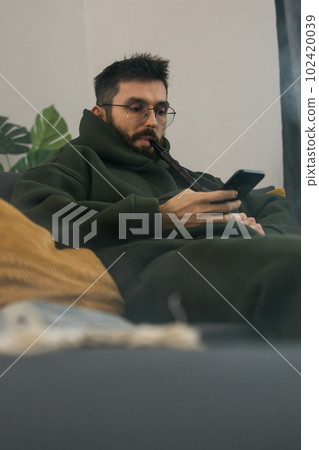 Bearded man is smoking hookah at home and blowing cloud of smoke - chill time and resting concept Bearded man is smoking hookah at home and blowing cloud of smoke - chill time and resting concept 102420039