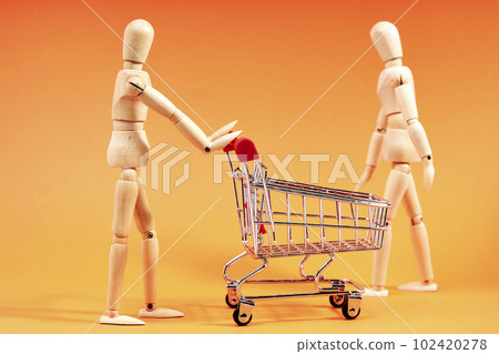 Dummy pushing a shopping trolley on an orange background Dummy pushing a shopping trolley on an orange background 102420278