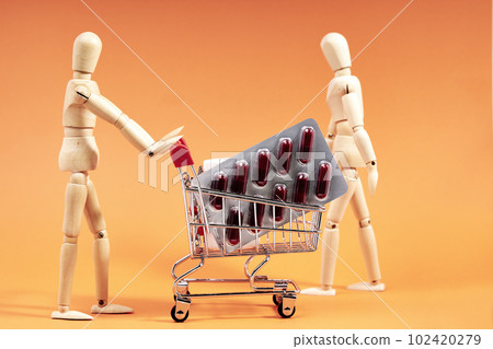 Dummy pushing a shopping trolley with medicines on an orange background. Health concept 102420279