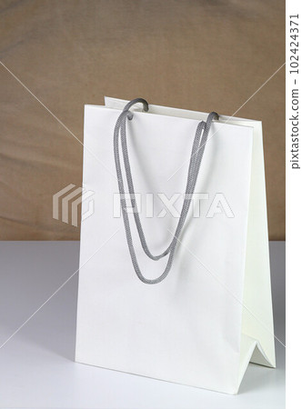 White paper shopping bag, present bag standing on white table with shallow focus. White paper shopping bag, present bag standing on white table with shallow focus. 102424371