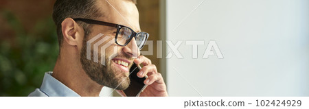 Mirthful man enjoying pleasant conversation and smiling Mirthful man enjoying pleasant conversation and smiling 102424929
