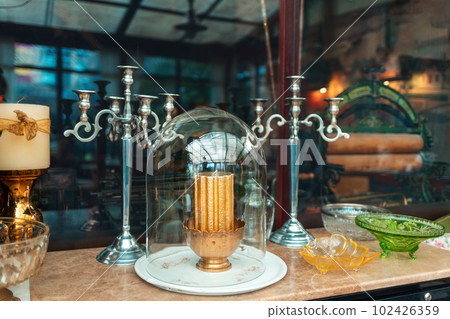 Vintage candle holder on wooden table with glassware. Stylish cafe or antique exhibition 102426359