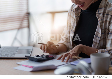 Asian accounting professional calculating household bills, reviewing and analyzing household bills, and filing tax returns. 102427620