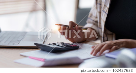 Asian accounting professional calculating household bills, reviewing and analyzing household bills, and filing tax returns. 102427688