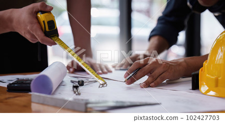 Architect and Engineer working with blueprints for architectural plan, engineer sketching a construction project, green energy concept Architect and Engineer working with blueprints for architectural plan, engineer sketching a construction project, green energy concept 102427703