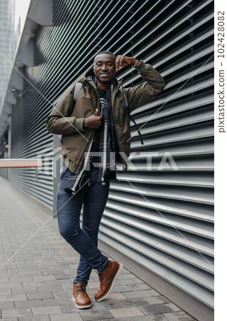 Portrait of man standing against grey wall. Portrait of African man smiling against gray wall. Portrait of man standing against grey wall. Portrait of African man smiling against gray wall. 102428082