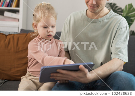 People with cochlear implant system. Kid study to hear with her father, learning with video on tablet. Installation cochlear implant on child girl ear for restores hearing. People with cochlear implant system. Kid study to hear with her father, learning with video on tablet. Installation cochlear implant on child girl ear for restores hearing. 102428628
