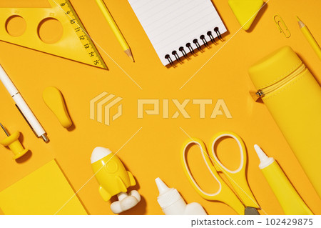 Assorted office and school white and yellow stationery. copy space for back to school or education craft office work concept. Bright Yellow monochrome scissors, rocket notepad. Achievement and success 102429875