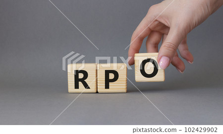 RPO - Recruitment Process Outsourcing symbol. Wooden cubes with words RPO. Businessman hand. Beautiful grey background. Business and RPO concept. Copy space. 102429902