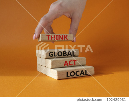 Think global act local symbol. Wooden blocks with words Think global act local. Beautiful orange background. Businessman hand. Business and Think global act local concept. Copy space. 102429981