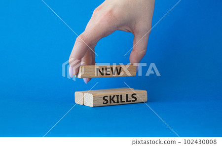 New skills symbol. Wooden blocks with words New skills. Beautiful blue background. Businessman hand. Business and New skills concept. Copy space. 102430008