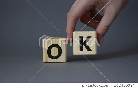 Ok symbol. Concept word Ok on wooden cubes. Businessman hand. Beautiful grey background. Business and Ok concept. Copy space. Ok symbol. Concept word Ok on wooden cubes. Businessman hand. Beautiful grey background. Business and Ok concept. Copy space. 102430084