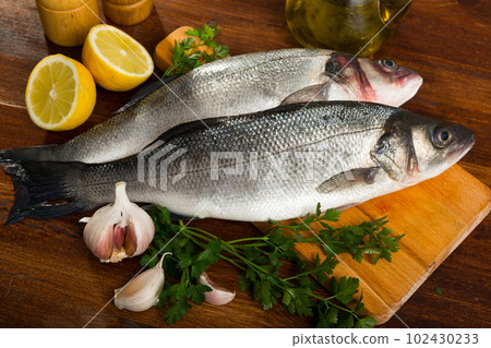 Cutting board with uncooked sea bass 102430233