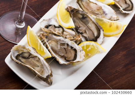 Opened raw oysters with lemon 102430660