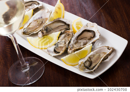 Tasty oysters with lemon on plate top view 102430708