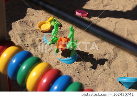 Plastic toys in the sandbox at the playground. Car, saucer, butterfly Plastic toys in the sandbox at the playground. Car, saucer, butterfly 102430741