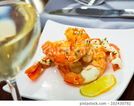 Split fried prawns with lemon and parsley on a white plate Split fried prawns with lemon and parsley on a white plate 102430792