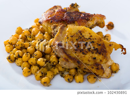 Fried chicken thighs served with garbanzo at plate on table Fried chicken thighs served with garbanzo at plate on table 102430891