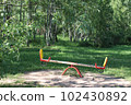 Swings on the playground. In the background are birches. Summer in the city  102430892
