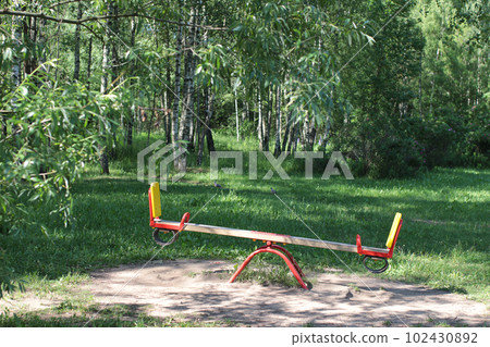 Swings on the playground. In the background are birches. Summer in the city  102430892