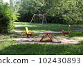 Swings on the playground. In the background are trees. Summer in the city  102430893