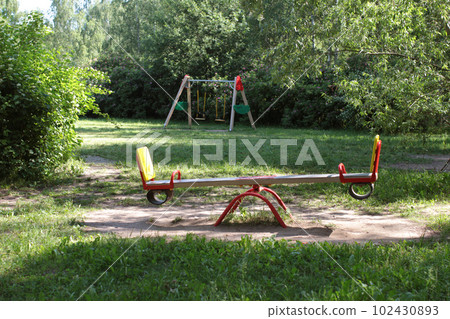 Swings on the playground. In the background are trees. Summer in the city Swings on the playground. In the background are trees. Summer in the city 102430893