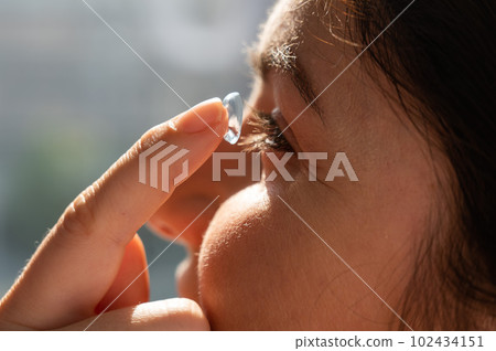 Close-up portrait caucasian woman putting on a contact lens. Close-up portrait caucasian woman putting on a contact lens. 102434151