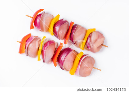 Uncooked mixed meat skewer with peppers.Skewers with pieces of raw meat, red, yellow and green pepper.Raw chicken leg meat skewers with vegetables, peppers, onions, on a white background.Top view. 102434153