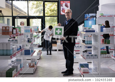 Elderly drugstore buyer standing with medicaments paper bag and looking at camera. Old man holding pills purchase in pharmacy, visiting medical retail store to buy supplements Elderly drugstore buyer standing with medicaments paper bag and looking at camera. Old man holding pills purchase in pharmacy, visiting medical retail store to buy supplements 102435160