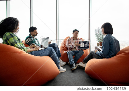 Male with AI project on laptop chatting with teammates Male with AI project on laptop chatting with teammates 102436389