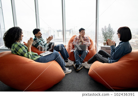 Man holding palms together while workmates applauding Man holding palms together while workmates applauding 102436391