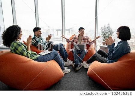 Man holding palms together while workmates applauding 102436398