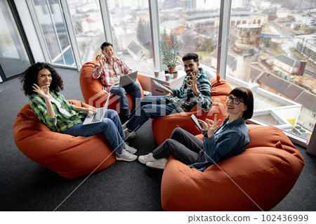 Males and females posing with gadgets in shared workspace Males and females posing with gadgets in shared workspace 102436999