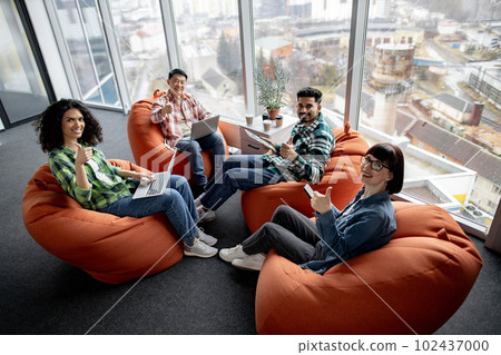 Males and females posing with gadgets in shared workspace Males and females posing with gadgets in shared workspace 102437000