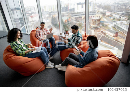 Managers using gadgets while resting in creative workspace Managers using gadgets while resting in creative workspace 102437013
