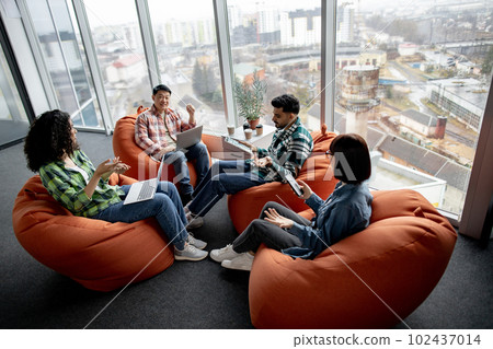 Managers using gadgets while resting in creative workspace Managers using gadgets while resting in creative workspace 102437014