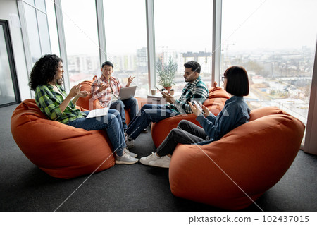 Colleagues discussing issues using devices in open office Colleagues discussing issues using devices in open office 102437015
