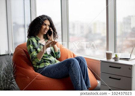 Lady having conversation on phone with coworkers indoors 102437023