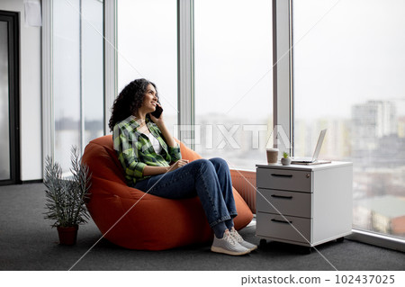 Lady having conversation on phone with coworkers indoors Lady having conversation on phone with coworkers indoors 102437025