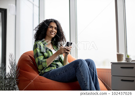 Woman chatting with colleagues via cell phone in office 102437026