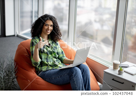 Businesswoman posing in beanbag with laptop at work Businesswoman posing in beanbag with laptop at work 102437048