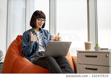 Pretty female having video conference on laptop in office 102437619