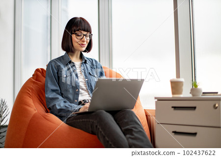 Pretty female having video conference on laptop in office Pretty female having video conference on laptop in office 102437622