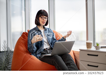 Pretty female having video conference on laptop in office Pretty female having video conference on laptop in office 102437623