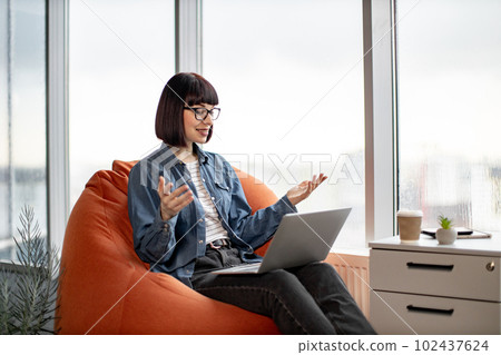 Pretty female having video conference on laptop in office Pretty female having video conference on laptop in office 102437624